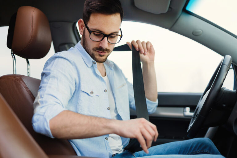 Driver fastening his seat belt in car