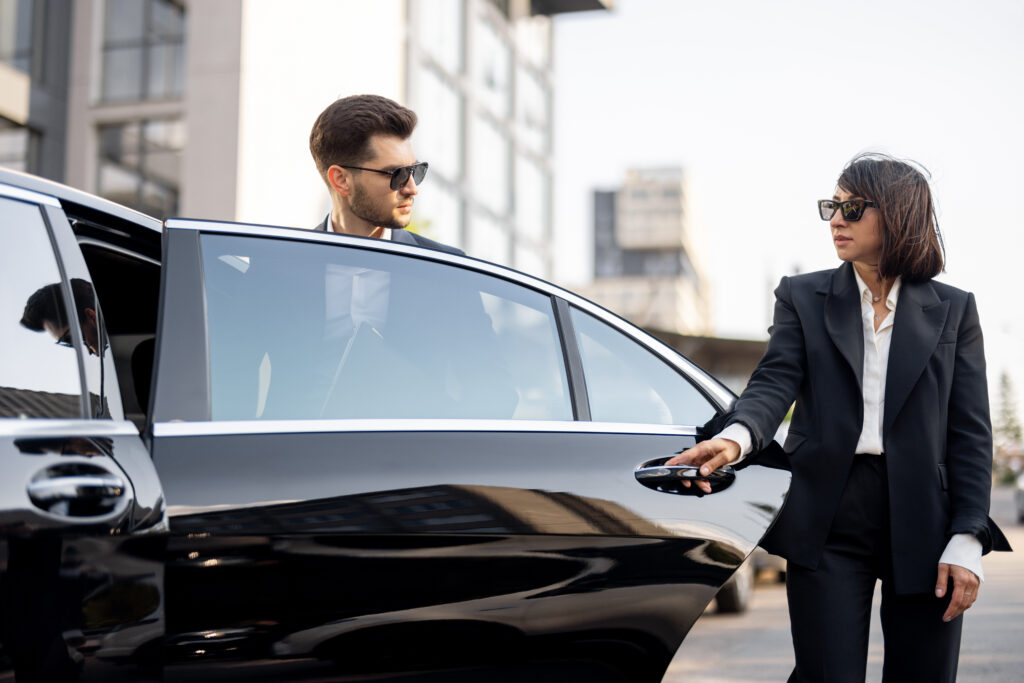 Female chauffeur helps a business man to get out of the car
